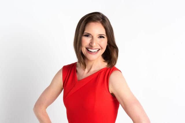Dr. Darria Long Smiling woman in a sleeveless red dress standing against a plain white background.